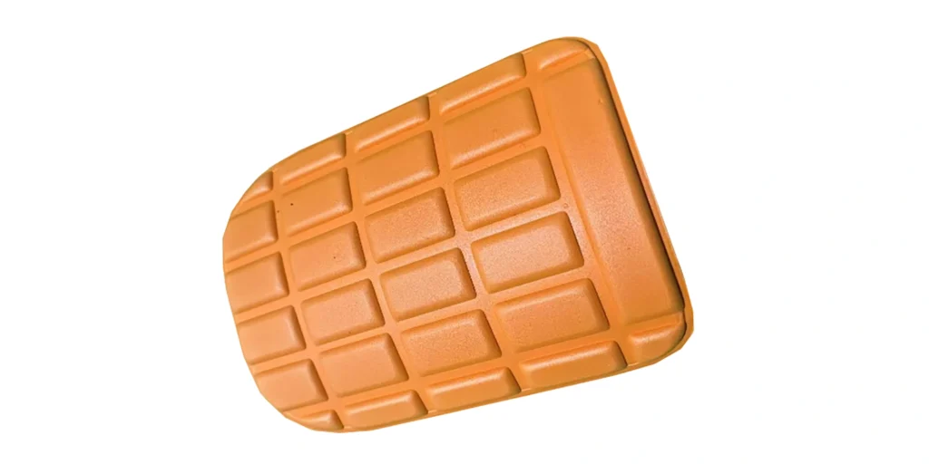 a single, orange - hued pad made of what appears to be rubber or a similar flexible plastic material. It has a rectangular shape with rounded edges. The surface features a grid pattern, consisting of evenly spaced, raised rectangular sections that form a series of small, square - like compartments. This design likely serves to enhance grip, provide cushioning, or aid in drainage, making it suitable for applications such as tool handles, floor mats, or protective padding.