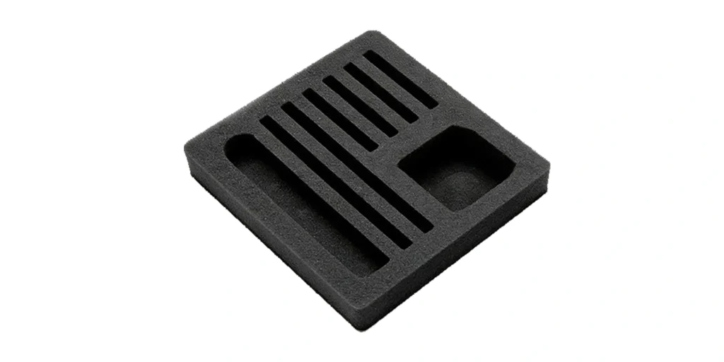 shows a square, black foam organizer tray with a structured layout. It features a series of evenly spaced, parallel slits in the center, flanked by a long, narrow recessed cavity on the left and a smaller, rounded cavity on the right. The smooth, matte black finish and precision-cut design make it ideal for securely holding and organizing small tools, accessories, or components during storage or transport.