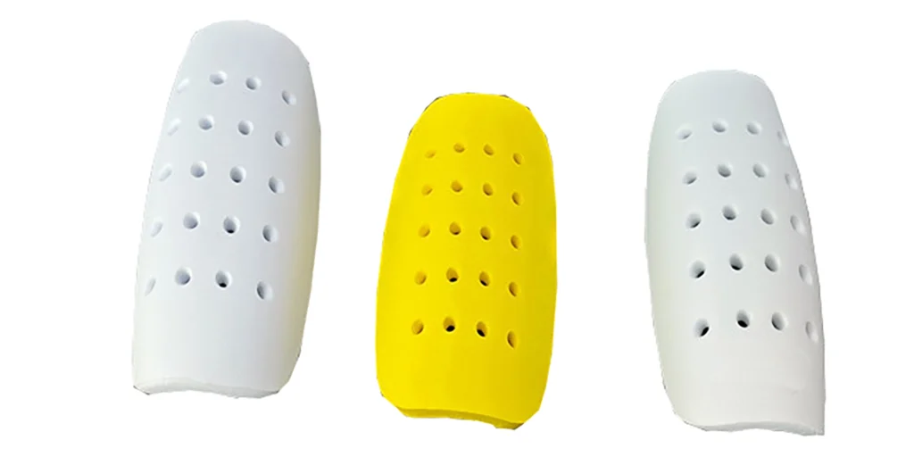 three soccer shin guards. Two are white and one is bright yellow. All have multiple ventilation holes to enhance breathability during use. These guards are designed to protect players’ shins during matches or training, likely made from lightweight, shock - absorbing materials for comfort and impact resistance.