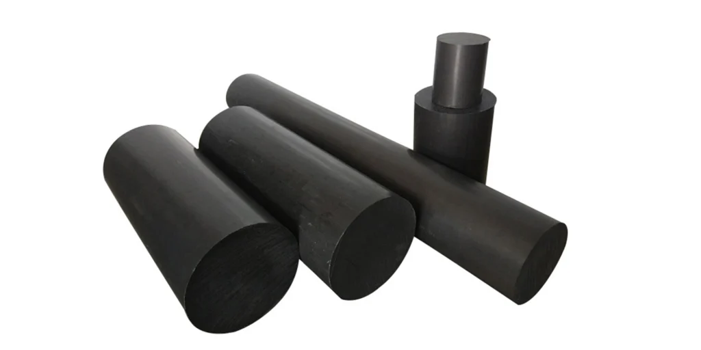 five cylindrical objects of varying sizes, likely made of a black material such as rubber or plastic. They are arranged in a casual manner with no specific pattern, suggesting they might be samples or parts used for some purpose. The largest cylinder is placed horizontally at the back, while the others are scattered around it, two lying on their sides and one standing upright. There’s also a smaller cylinder that appears to have been cut shorter than the rest, positioned vertically near the center-right of the image.