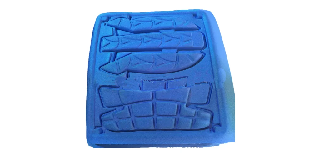 shows a rectangular, bright blue foam insert with a series of precision-machined cavities. The top section features three rows of fish-shaped cutouts, while the lower section has rectangular and grid-like cavities, all tailored to hold specific items securely. The smooth, vibrant blue finish and custom-fit design make it ideal for protecting and organizing specialized components (such as fishing lures or crafts) during transport or storage.