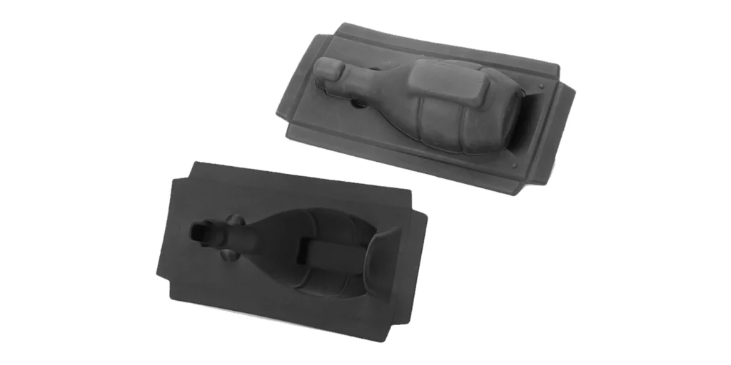 displays two black foam packaging inserts designed for protecting a wine bottle and a glass during transport. One insert features a raised, molded shape of a wine bottle and a glass, while the other has a matching hollow cavity to hold the items securely. Both inserts have a smooth, matte black finish and are presented against a plain white background, highlighting their precise, custom-fit design for fragile item protection.