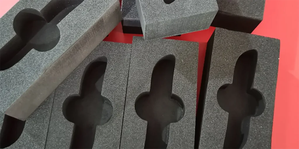 AlternativeText: Several black foam pieces with custom - cut shapes on a red background. Caption: Black Foam Inserts with Intricate Cut - Out Designs Description: This image displays multiple black foam pieces, each featuring precisely - cut, symmetrical shapes. The textured surface of the foam and the vibrant red background highlight the detailed cut - outs, which are likely designed to hold objects securely. These foam inserts could be used for protective packaging or organizational purposes, emphasizing functionality and precision in their design.