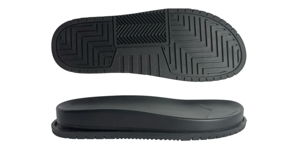 a black shoe sole with two distinct views. The top view shows a smooth, flat upper surface, while the bottom view reveals a detailed tread pattern featuring geometric shapes and lines. The sole appears to be made of a sturdy material, likely designed for durability and traction.