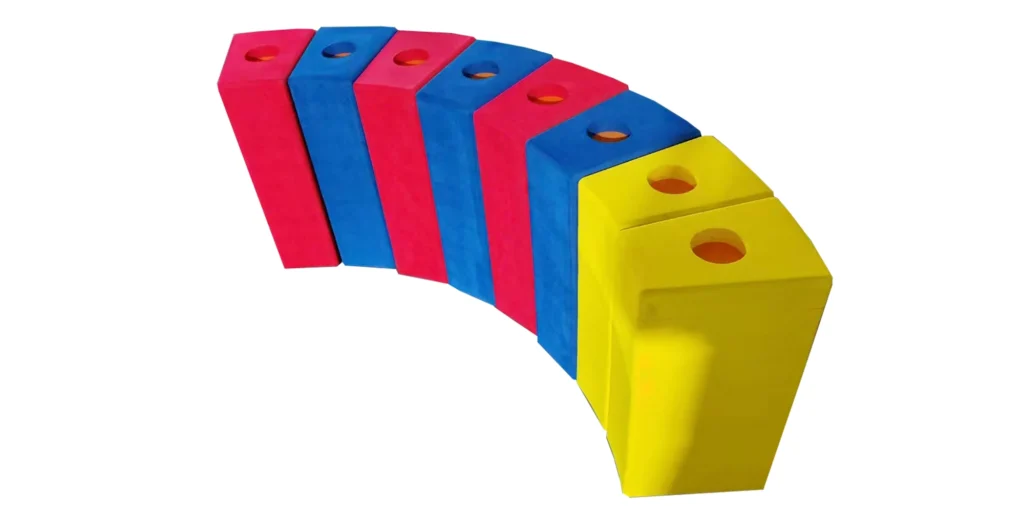 AlternativeText: “Colorful blocks in red, blue, and yellow arranged in a curved pattern, each with a circular hole on top.” Caption: “Curved arrangement of vibrant red, blue, and yellow blocks, each featuring a circular hole.” Description: “This image showcases a series of blocks forming a gentle curve. The blocks alternate between red and blue initially, with the final two blocks being yellow. Each block is a rectangular prism with a circular hole on its top surface. The vivid colors—red, blue, and yellow—create a lively visual pattern. The curved arrangement adds a dynamic, aesthetically pleasing element to the display, making it engaging to observe.”