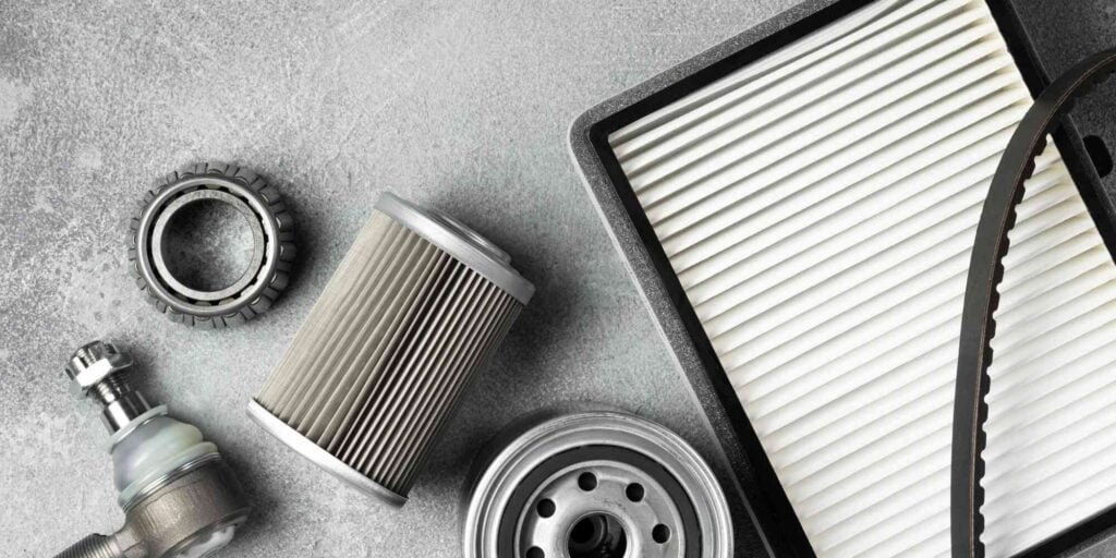 A collection of car parts with various components arranged on a gray background. They include filters, air filters, and brake pads. These items are placed on a table and appear to be ready for replacement or repair. Their presence suggests that the owner is considering maintaining the vehicle and improving its performance.