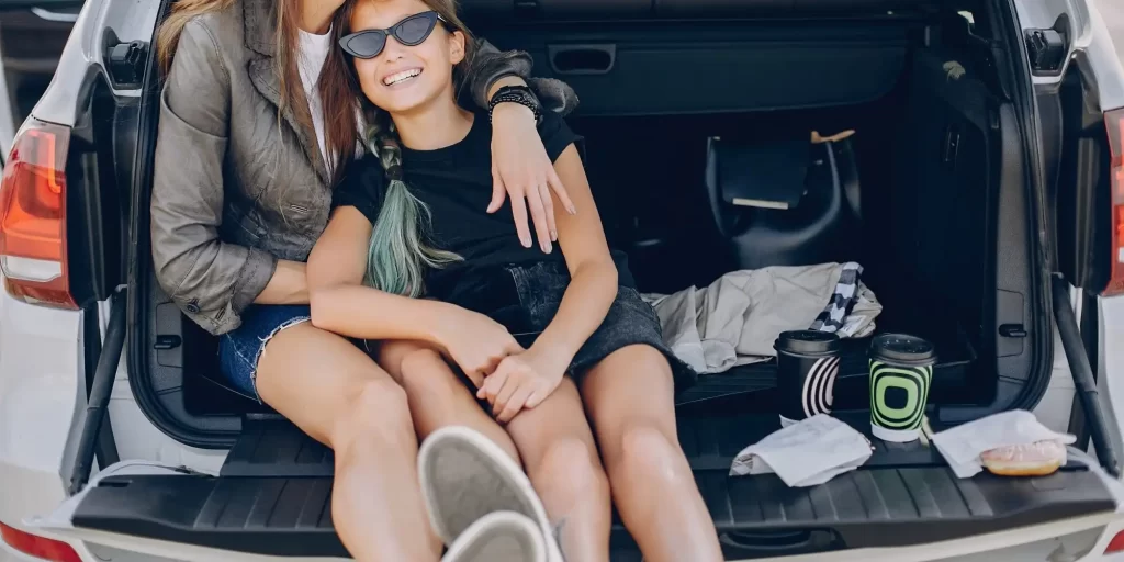 A mother and her daughter sitting in the trunk of a The roar of the car's engine carries across the city. The sunlight pours through the windows of the car as if telling some story. In the back seat of the car. Daughter quietly looks out the window; The mother gently stroked her hair and She gently stroked her hair and comforted her. The world outside the car window is so beautiful. It's so refreshing and mesmerizing; And this mother and daughter. The mother and daughter felt the warmth and happiness of life at this moment.