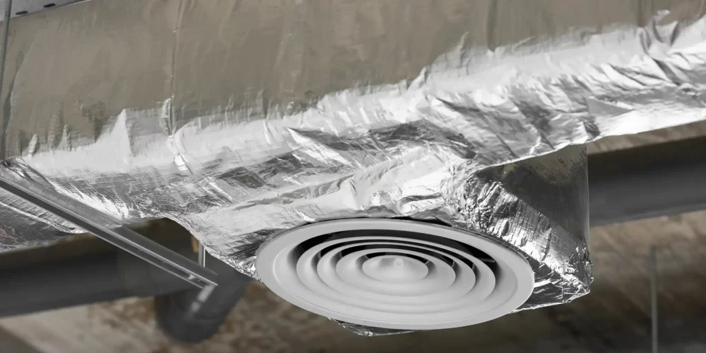 The aluminum ceiling above the ducts appears to be covered with a layer of silver. It seemed to extend from the ventilation system or the air conditioning unit. Between the black metal pipe and the white ceiling, a silver glow shines throughout the room. It could be a vent, a filter, or part of a ventilation duct. Its presence makes the air in the room fresher and more comfortable