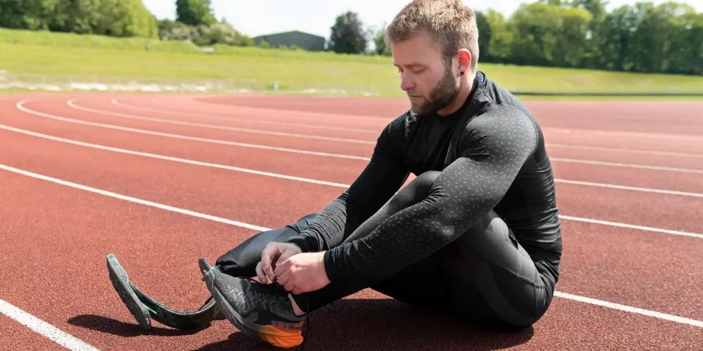 The picture shows a man sitting on the track, tying his sneakers.