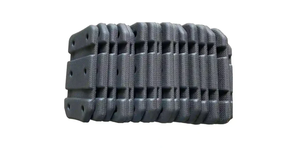 shows a black, flexible industrial cable carrier (also called a drag chain). It features a segmented, interlocking design with a textured surface and integrated slots, which is designed to protect and route cables or hoses in machinery. The chain is presented against a clean white background, highlighting its robust, modular construction that allows for bending and movement while safeguarding internal components. If you need, I can help you generate similar descriptions for other industrial components like this.
