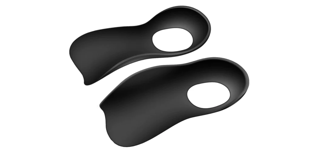two identical black foot support accessories. Each has a smooth, curved shape that conforms to the foot’s contours, with an oval - shaped cutout near the center. The minimalist, matte - black finish gives them a modern and understated look, suggesting they might be used for comfort, alignment, or specialized footwear support. Their design hints at both functionality (like arch or pressure relief) and a contemporary aesthetic.