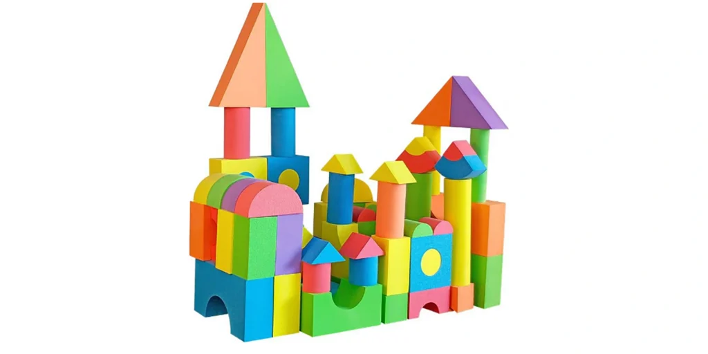 AlternativeText: “Colorful foam building blocks forming a playful structure with towers and arches.” Caption: “A vibrant structure of multicolored foam blocks, featuring towers, arches, and geometric shapes.” Description: “This image showcases a lively arrangement of foam building blocks in various colors and shapes. On the left, a tall tower with a triangular roof (orange and green sections) sits atop pink and blue columns. Below, a row of rainbow - colored arched blocks adds whimsy. To the right, multiple towers with yellow, red, and blue roofs rise from cylindrical and rectangular blocks. Blocks in bright hues—red, blue, green, yellow, purple, and orange—create a visually appealing design. Geometric shapes (triangles, circles, rectangles) foster a playful, creative atmosphere. The white background highlights the vivid colors and intricate arrangement.”