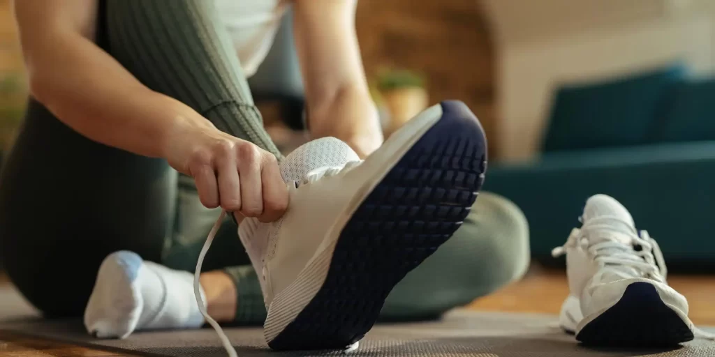 a person sitting on a yoga mat, tying the laces of a sports shoe. The image focuses on the shoe, indicating a possible emphasis on sports footwear, which could be linked to a discussion about the materials used in such shoes, like EVA foam. EVA foam (ethylene-vinyl acetate) is often used in sports and medical footwear due to its cushioning properties, which provide support and absorb impact. This lightweight material can be crucial for both athletic performance and for those requiring medical orthotics, offering comfort without sacrificing durability. If you’re looking to explore the benefits of EVA foam in medical footwear, it’s important to consider factors such as the foam’s density, which affects the level of support and shock absorption, as well as its integration into the overall design of the shoe or orthotic device. EVA foam can be engineered in various levels of firmness, catering to different needs, from sports performance to corrective orthotics.