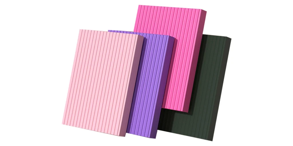 four rectangular blocks in varying shades of colors, each exhibiting vertical stripes on its surface. From left to right, the first block is light pink, followed by a darker shade of pink, then a deep purple, and finally a dark green. These blocks are set against a stark white background, which accentuates their vibrant hues and striped patterns. The arrangement of these blocks creates a visually appealing contrast, with the colors transitioning from lighter to darker tones. The precise placement and alignment of the blocks suggest a sense of order and symmetry in the composition. Overall, the image presents a harmonious blend of color and pattern, evoking a sense of balance and harmony.