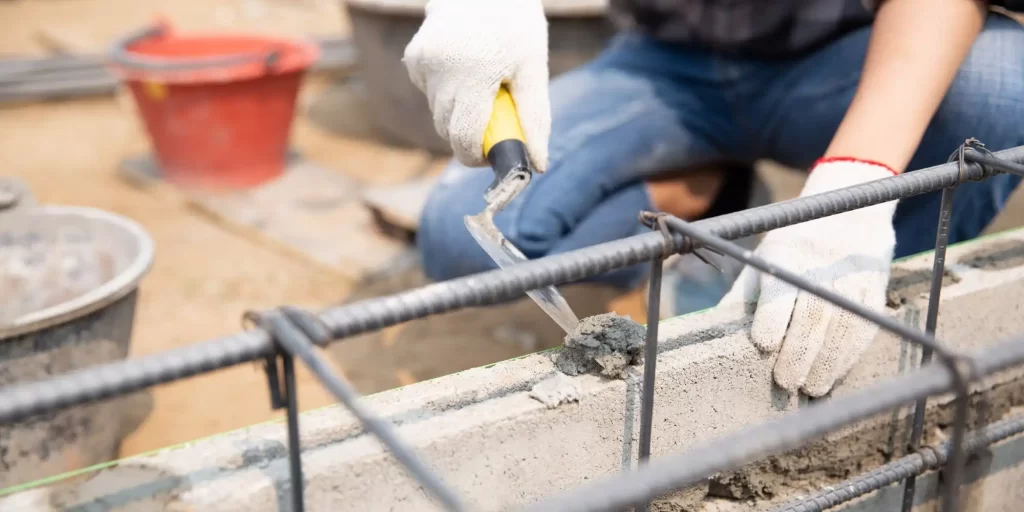 The picture shows a worker working on concrete using tools, which include hammers and scissors.
