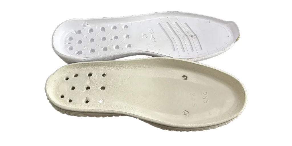 a sole is white, designed with numerous holes and some engraved markings including "XG - 01" and "41". The other sole is beige, also having several holes and engraved with "255" and other symbols. Both soles appear to be made of lightweight materials, likely intended for use in footwear to provide comfort and specific functional features.