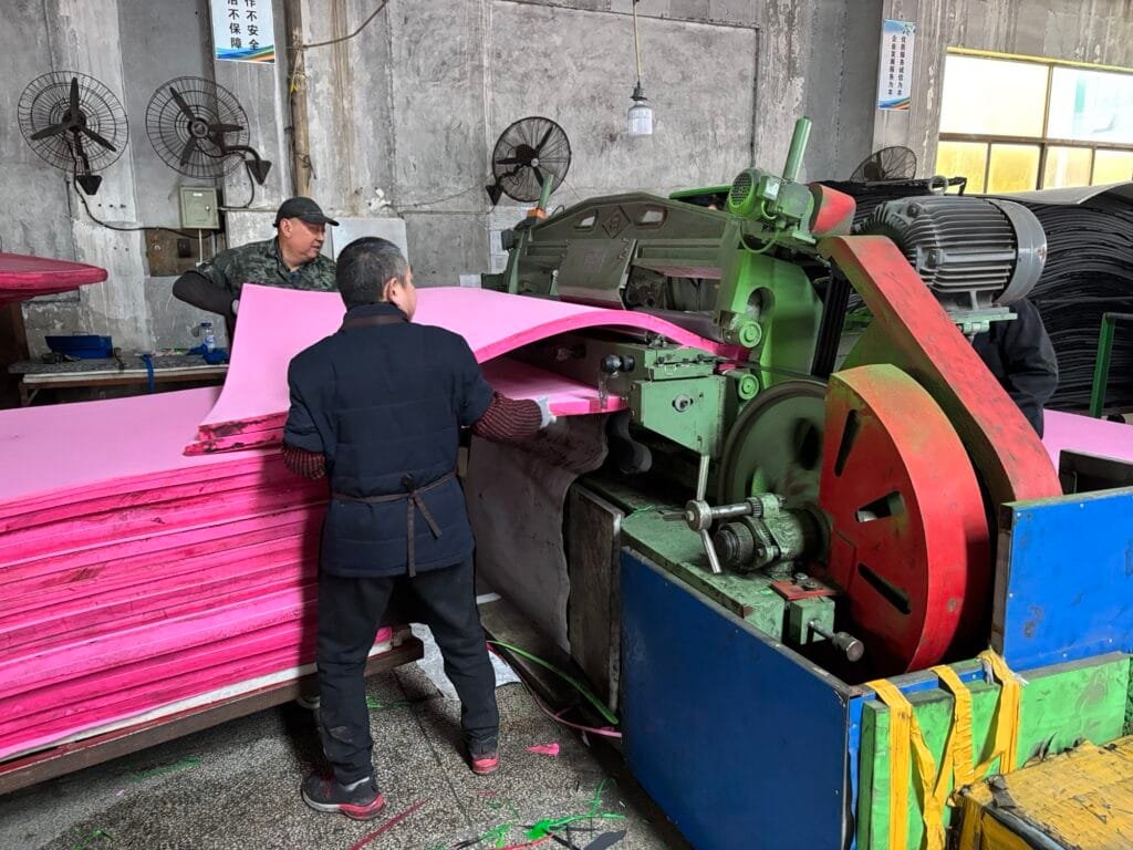 Four workers are splitting the EVA foamed sheets into multiple layers.